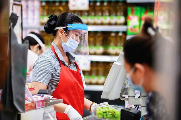 female supermarket cashier in medical protective mask working at supermarket. covid-19 spreading outbreak