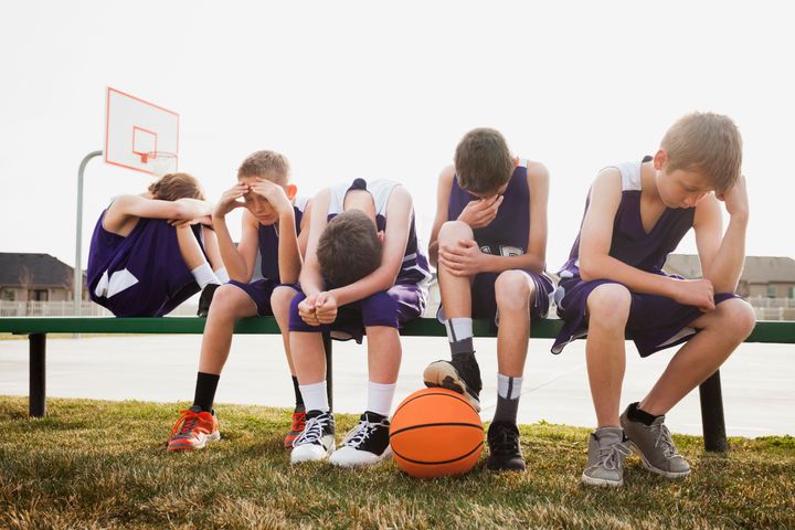 Caucasian basketball team sulking by court