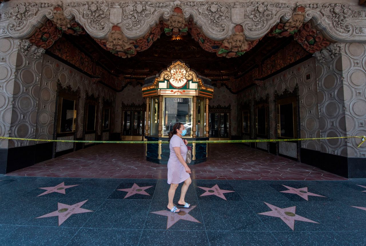 A woman walks past the El Capitan Theater on Hollywood Boulevard in Los Angeles on June 12, 2020. As coronavirus cases in California hit a record high this week, the state is rolling back reopening plans.