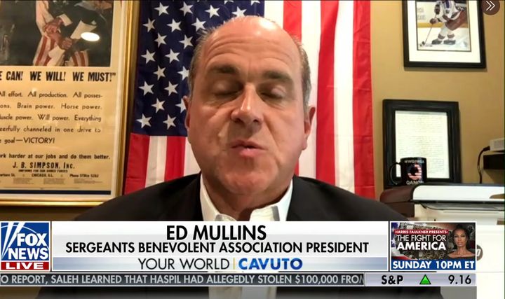Ed Mullins, president of the Sergeants Benevolent Association, appears Thursday on Fox News with a black "QAnon" coffee mug behind him.