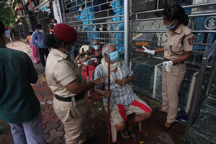 Police officers comfort a man during a medical check-up at a temple in Mumbai, India on July 18, 2020. India has become the third country after the United States and Brazil, to cross 01 million COVID-19 cases. (Photo by Himanshu Bhatt/NurPhoto via Getty Images)