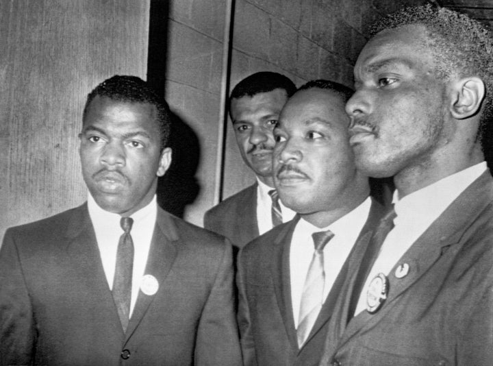 Reverend Martin Luther King Jr., (center) is escorted into a mass meeting at Fisk University in Nashville. His colleagues are, left to right, John Lewis, national chairman of the Student Non-Violent Committee and Lester McKinnie, on of the leaders in the racial demonstrations in Nashville recently. King gave the main address to a packed crowd. (Photo by Bettmann Archive/Getty Images)