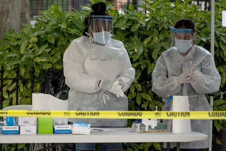 Two medical workers wearing PPE are seen changing their gloves at a free coronavirus testing location outside Washington Square Park, New York.