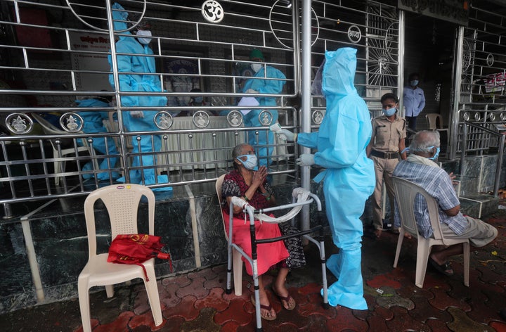 A health worker screens an elderly woman for COVID-19 symptoms at a temple in Mumbai, India, Saturday, July 18, 2020. (AP Photo/Rafiq Maqbool)