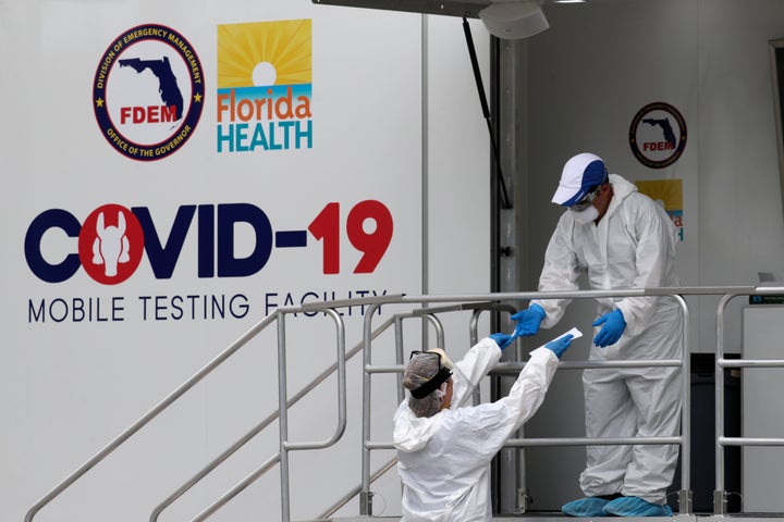 Health care workers work at a walk-up COVID-19 testing site during the coronavirus pandemic, Friday, July 17, 2020, in Miami Beach, Fla. The mobile testing truck is operated by Aardvark Mobile Health, which has partnered with the Florida Division of Emergency Management. People getting tested are separated from nurses via a glass pane. (AP Photo/Lynne Sladky)