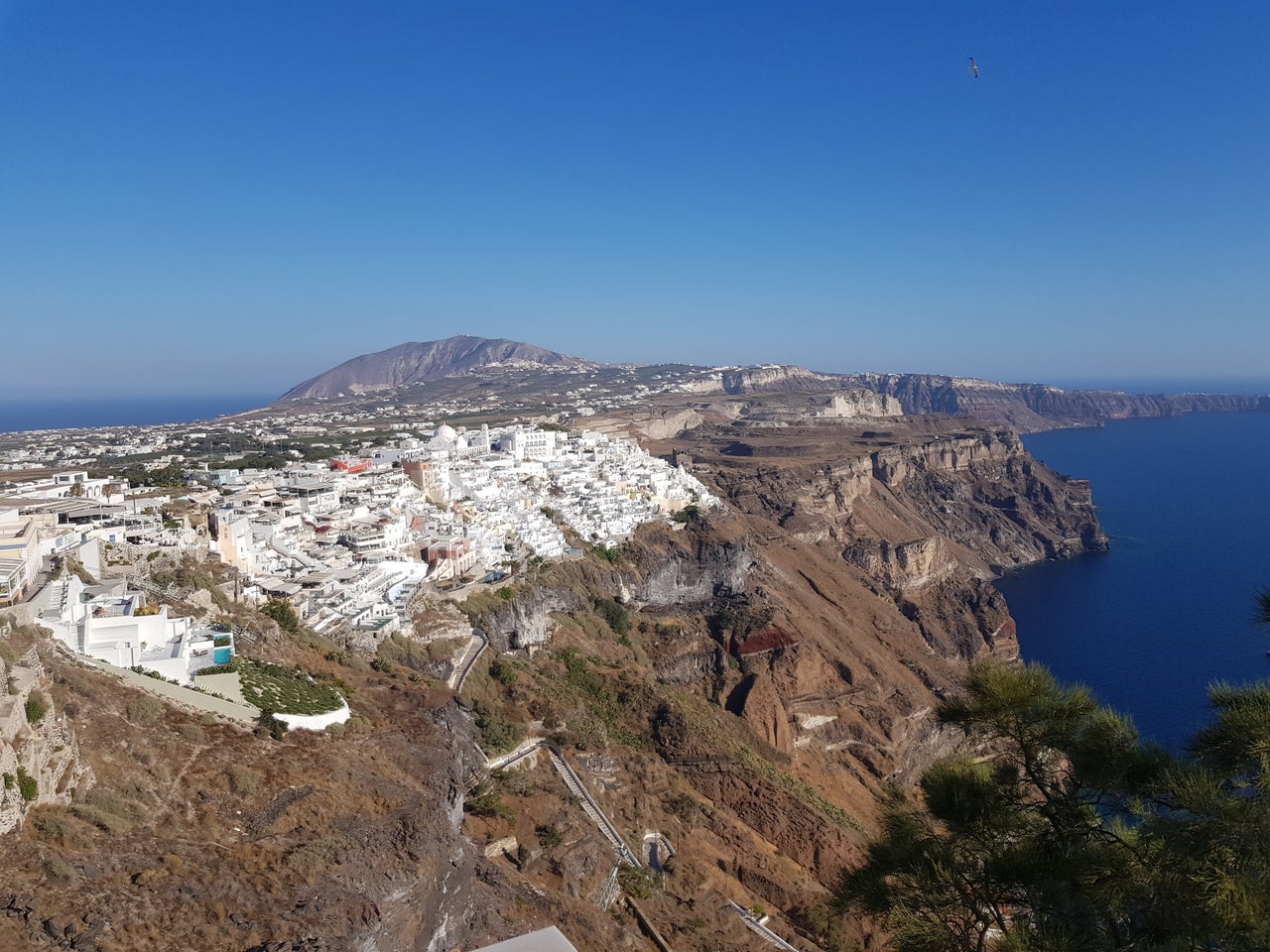 Η άγρια ομορφιά της Καλντέρας το πρωί φωτογραφημένη από τα Φηρά. Και στο βάθος ο Προφήτης Ηλίας.