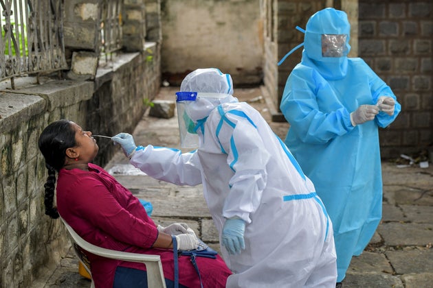 A health official takes a swab sample from a patient at a COVID-19 point set up by Bangalore municipality...