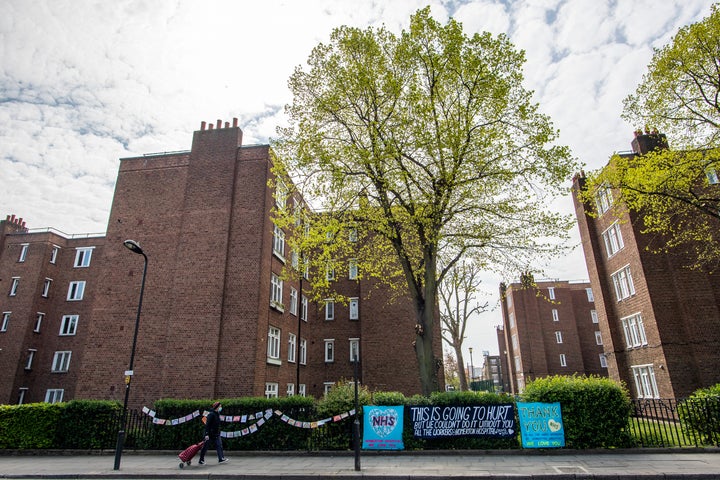 A woman in a face mask walks past a sign in tribute to NHS workers outside the Homerton Hospital in east London