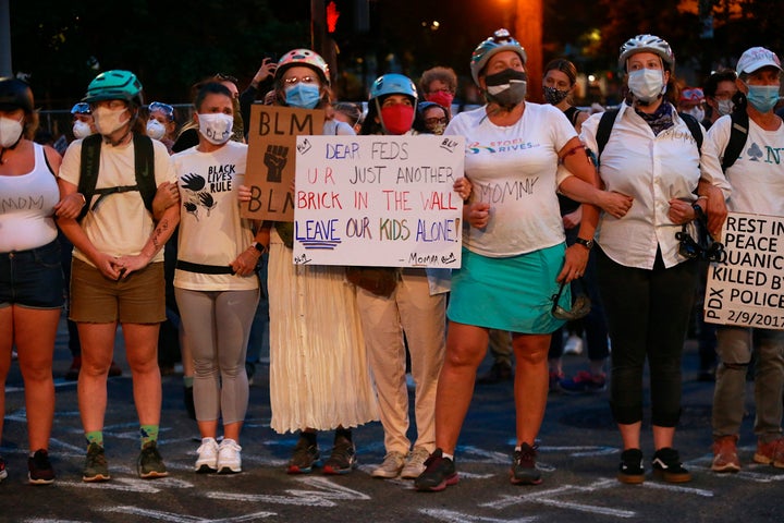 A group of mothers stand arm-in-arm outside the federal building and Justice Center in downtown Portland on Saturday.