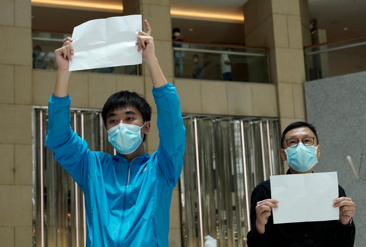 Protesters raise white papers as they gather at a shopping mall in Central during a pro-democracy protest against Beijing's national security law in Hong Kong on Tuesday. A few of protesters were detained and released shortly afterward.