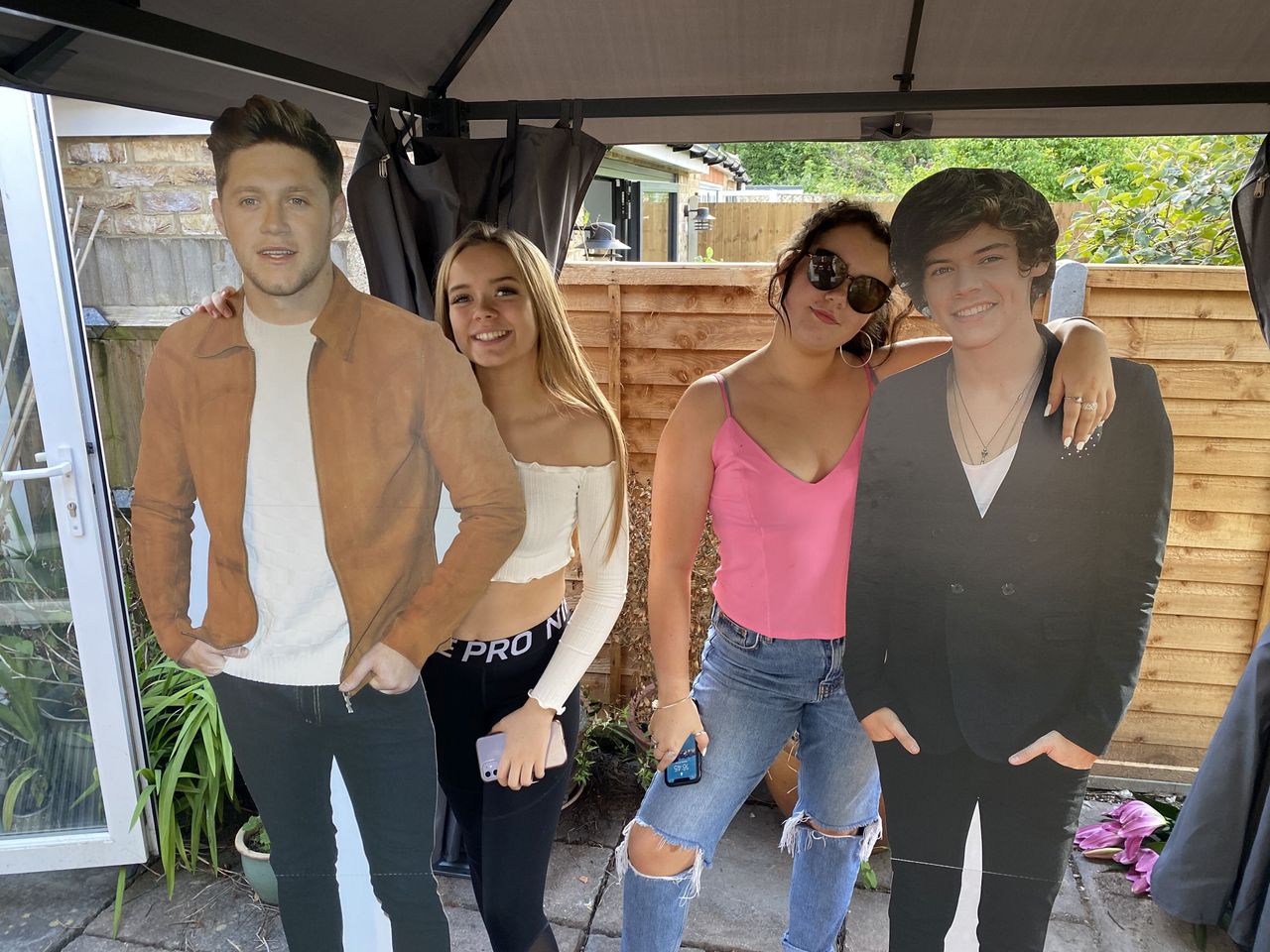 One Direction fan Millie, right, with her sister Jessie, left, standing with One Direction cutout figures of Harry and Niall