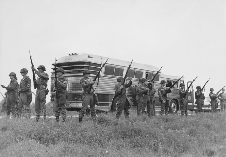 Members of the U.S. military guard a bus carrying civil rights activists known as Freedom Riders while they travel into Jackson, Mississippi, in May 1961.