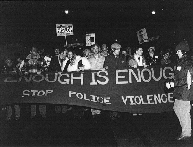 Following the bathhouse raids, protestors march from Queen's Park to Toronto Police division 52, carrying a banner that reads "Enough is Enough."