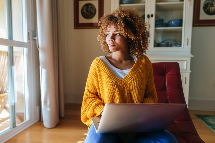 Young woman sitting on chaiselongue using laptop at home