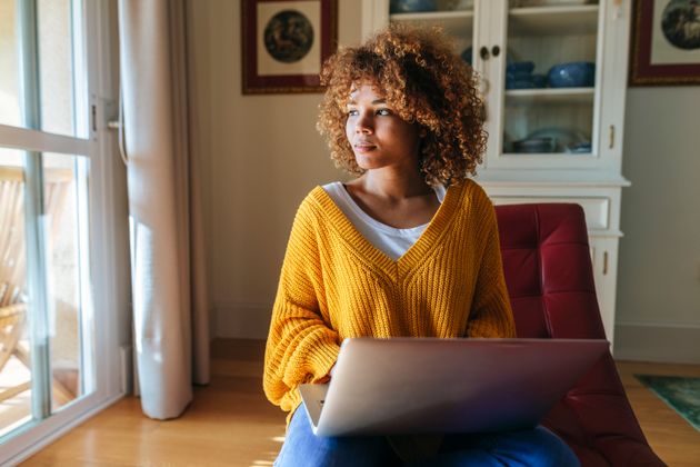 Young woman sitting on chaiselongue using laptop at home