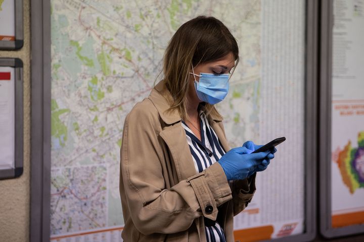 A woman uses a mobile phone while waiting for a train in Milan, Italy, on May 4, 2020.