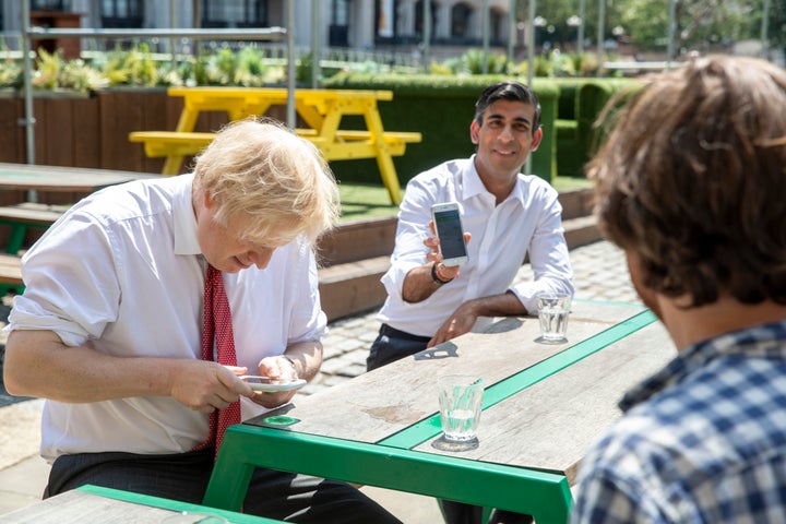 British Prime Minister Boris Johnson and Chancellor Rishi Sunak use their phones during a visit to a restaurant in London, June 26, 2020. The U.K. government had to scrap its initial effort to develop a contact-tracing app.