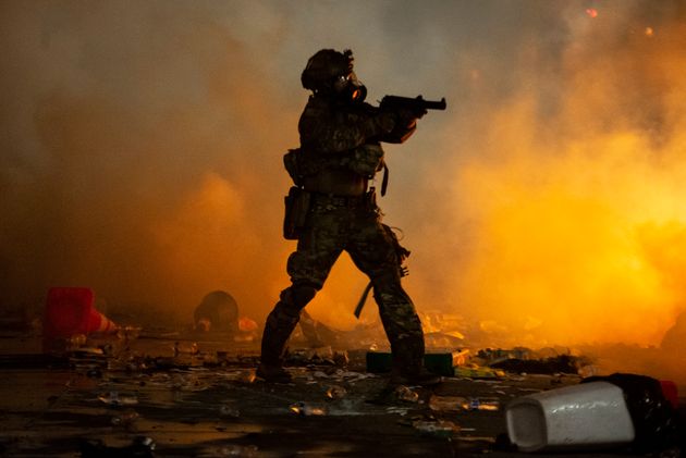 A federal officer points a less-lethal weapon toward a crowd of a few hundred protesters in front of the Mark O. Hatfield U.S. Courthouse on July 23, 2020 in Portland