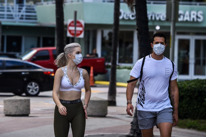 Tourists wearing masks walk near the closed Miami Beach on March 19.