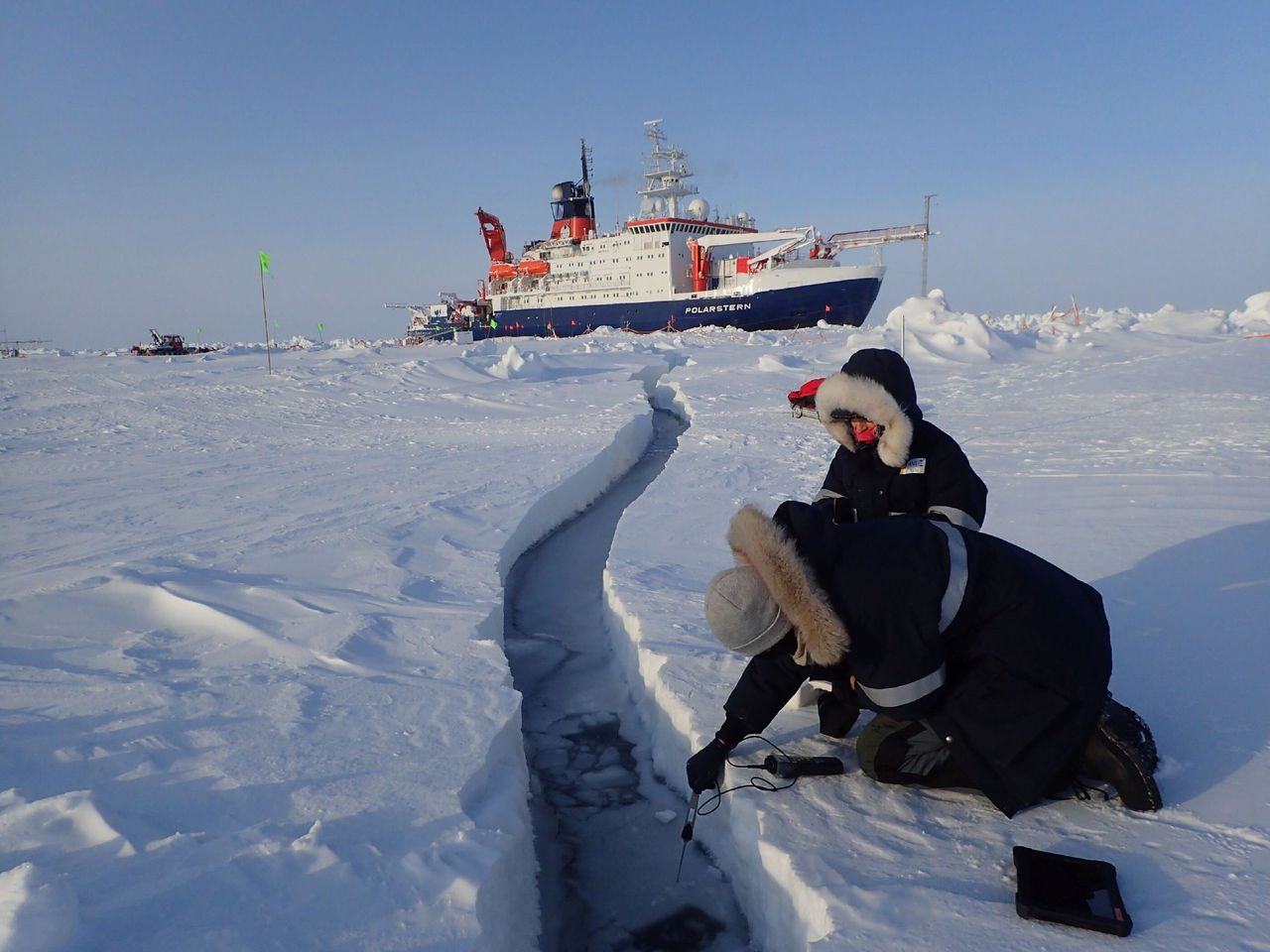 Researchers sample water for lead, with Polarstern in the background.