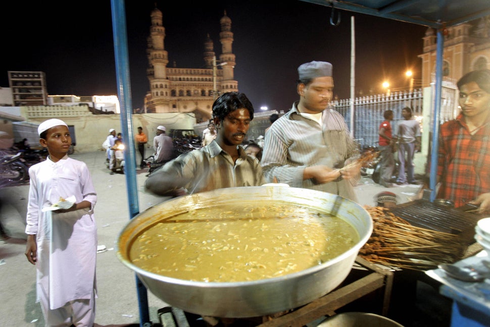 HYDERABAD, INDIA: An Indian vendor prepares kebabs and non-vegetarian delicacies in his stall outside the Mecca mosque with the Char Minar in the background in Hyderabad, 20 October 2005. I