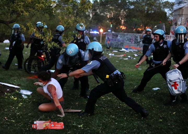 A protester and Chicago police clash after protesters tried to topple the Christopher Columbus statue in Grant Park during a