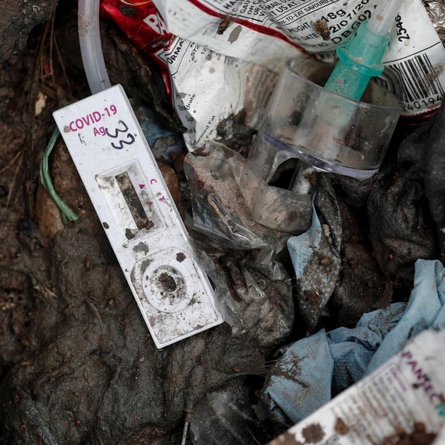 A COVID-19 testing kit lies on the floor at a landfill