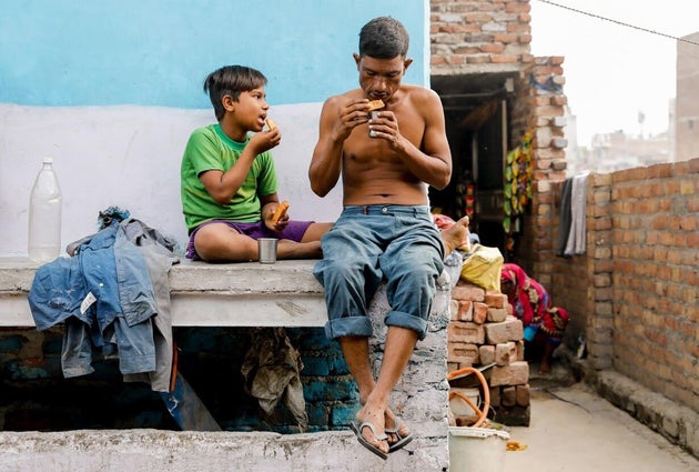 Khan eats breakfast with his son Latif outside their house which is next to a