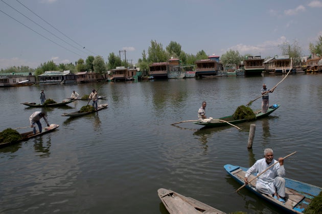 Kashmiri boatmen employed by the Jammu and Kashmir government remove weeds from the Dal Lake in Srinagar,...