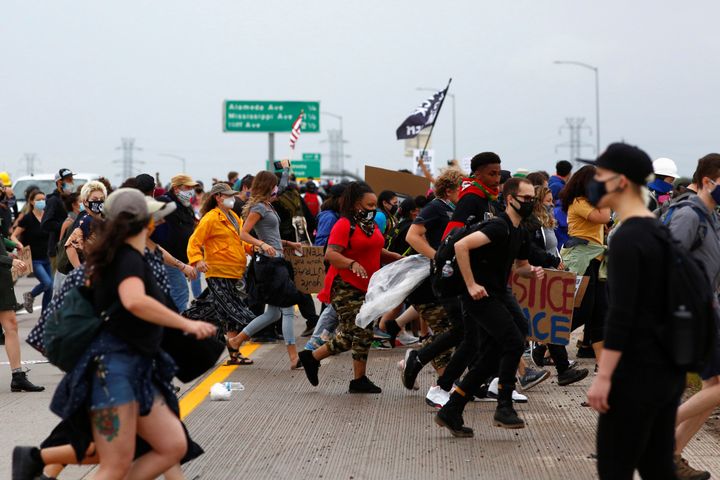 People run for cover moments after a driver in a blue Jeep rammed through the crowd of protesters and shots were fired during a march on Interstate 225 in Aurora, Colorado.