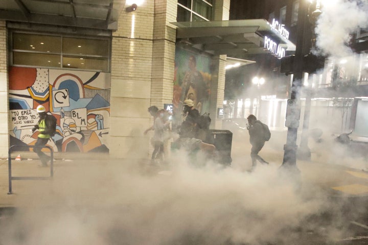 Demonstrators walk away from tear gas deployed by federal officers during a Black Lives Matter protest Sunday, July 26, 2020,