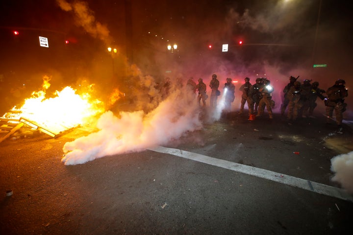 Federal officers clear a street where demonstrator had set a fire during a Black Lives Matter protest at the Mark O. Hatfield