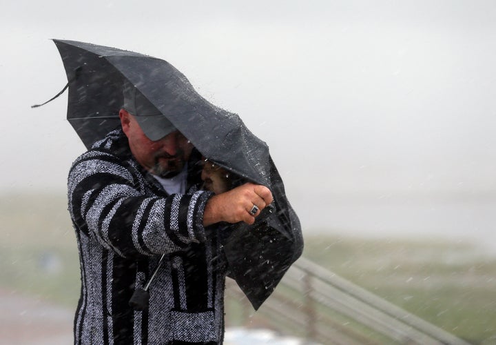 A man holds the front on his umbrella as he fights heavy rain and wind on Seawall Boulevard, Saturday, July 25, 2020, in Galveston, Texas. (Godofredo A. Vásquez/Houston Chronicle via AP)