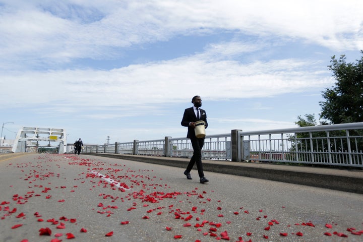 A man places flower petals on the Edmund Pettus Bridge ahead of Rep. John Lewis' casket crossing during a memorial service for Lewis, Sunday, July 26, 2020, in Selma, Ala. (AP Photo/Brynn Anderson)