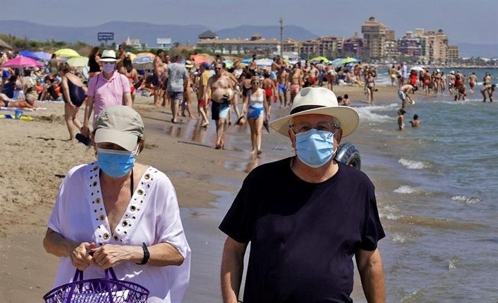 Varias personas pasean por una playa