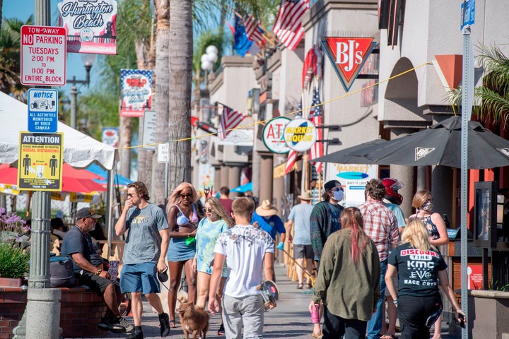 Beachgoers, many maskless, walk down Main Street in Huntington Beach, California. Residents of the city south of Los Angeles have been notably anti-mask and lockdown-averse, in spite of rising coronavirus cases in the region.