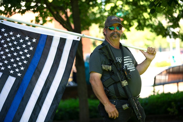 Josh Bradley holds a thin blue line flag in in Vancouver, Wa., on June 26, 2020, during a rally against a state order to wear masks.