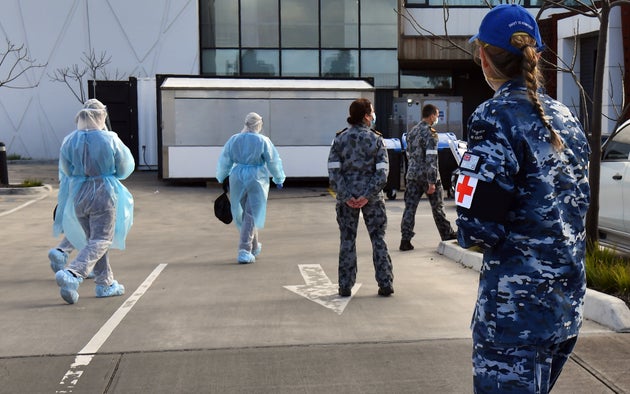 Australian Defence Force personnel escort their staff into the Epping Gardens aged care facility in the Melbourne suburb of Epping on July 28, 2020 as the city battles fresh outbreaks of the COVID-19 coronavirus.