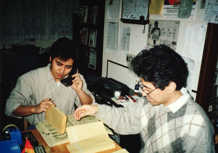 「すこたん企画」時代、事務所で作業をする伊藤悟さん（右）と簗瀬竜太さん。1990年代後半の撮影。