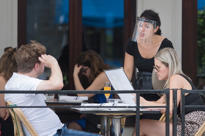 A server wears a face shield as she takes an order at a restaurant in Montreal.