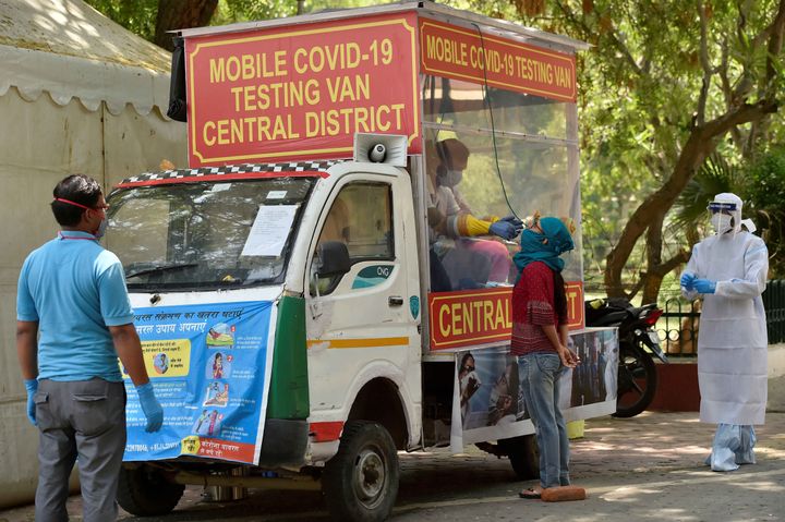 A health official collects a sample from a medical staff of a hospital from a mobile Covid-19 testing van onApril 30, 2020 in New Delhi.