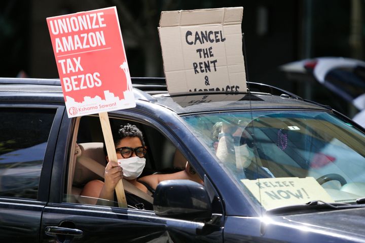 People drive around the block with anti-Jeff Bezos signs as they participate in a "car caravan" protest at the Amazon Spheres to demand the Seattle City Council tax the city's largest businesses in Seattle, Washington on May 1, 2020.