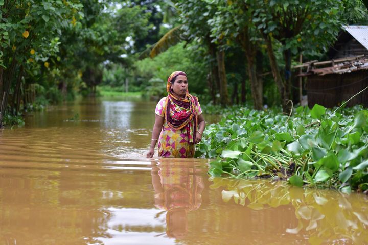 A woman wades through a flooded street in Nagaon district of Assam on 22 July 2020. 