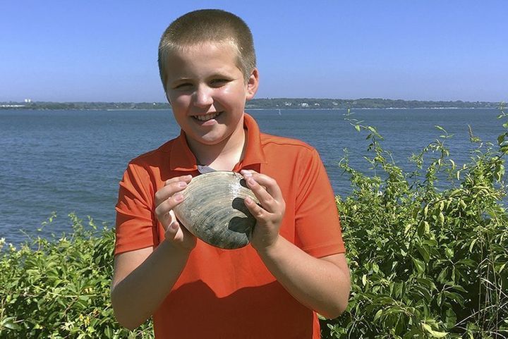Cooper Monaco holds the large quahog he found Monday while clamming with his grandfather in Westerly, R.I. The quahog is more than five inches across and weighing more than two pounds, and is among the largest ever harvested in the state.