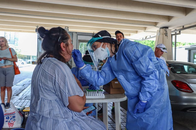 PROMACHONAS, MACEDONIA, GREECE - 2020/07/13: A healthcare worker taking swab tests from a woman at the border.
Travelers entering Greece at the Greek-Bulgarian borders of Promachonas - Kulata are tested for Covid-19 and should wait in a specific place for 24 hours, quarantined until the test results come back. (Photo by Nik Oiko/SOPA Images/LightRocket via Getty Images)