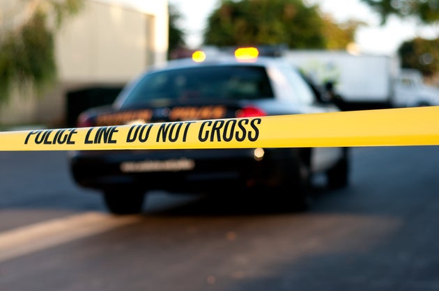 A blurred police car in the background behind crime scene tape.