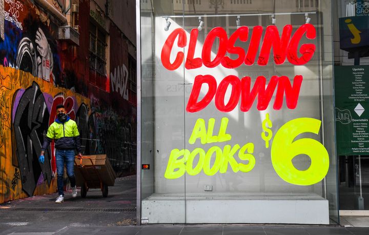 A worker walks past a empty shop in Melbournes central business district on August 3, 2020 after the state announced new restrictions as the city battles fresh outbreaks of the COVID-19 coronavirus. 