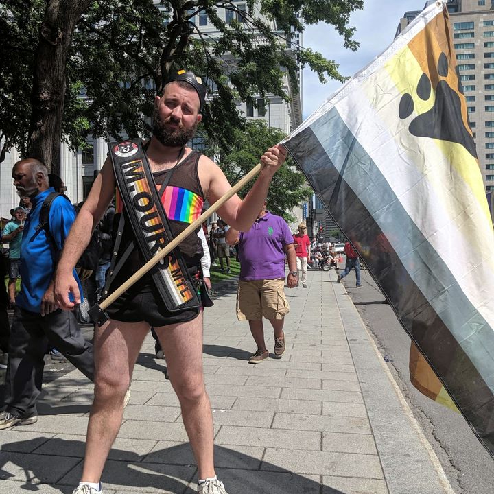 Julien Serre au défilé de la Fierté 2019, arborant sa bannière de Monsieur Ours et le drapeau de la communauté ours.