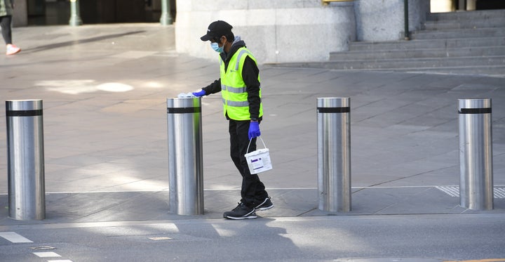 A worker cleans posts in Melbourne on Aug. 3, 2020 after the state announced new restrictions as the city battles new outbreaks of COVID-19. 