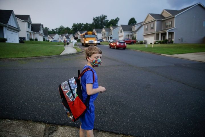 A 7-year-old boy wearing a mask waits at the bus stop on Aug. 3, the first day of school in Dallas, Georgia.